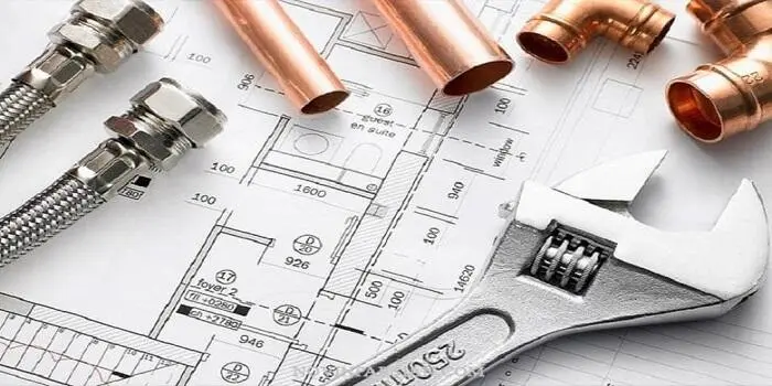 تصویر لویه های مسی و آچار فرانسه روی یک نقشه ساختمان