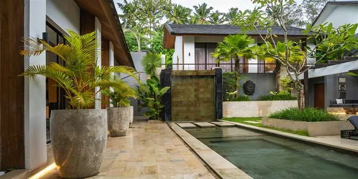 طراحی فضای سبز - صفر تا صد هرچیزی که باید بدانید _ محوطه بیرونی یک ویلا که گلدان های سنگی بزرگ و استخر در آن وجود دارد.