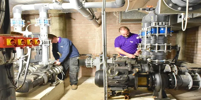 تاسیسات مکانیکی شامل چیست _ انواع تاسیسات مکانیکی _ تصویر دو تعمیرکار در میان تاسیسات مکانیکی ساختمان