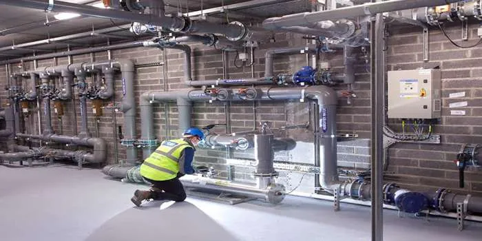 فردی در حال چک کردن تاسیسات مکانیکی ساختمان است.