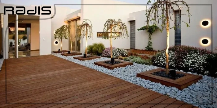 همه چیز درباره طراحی فضای سبز ویلا _ تصویری از محوطه یک ویلا که با کفپوش قهوه ای و درختان زیبا کار شده است.