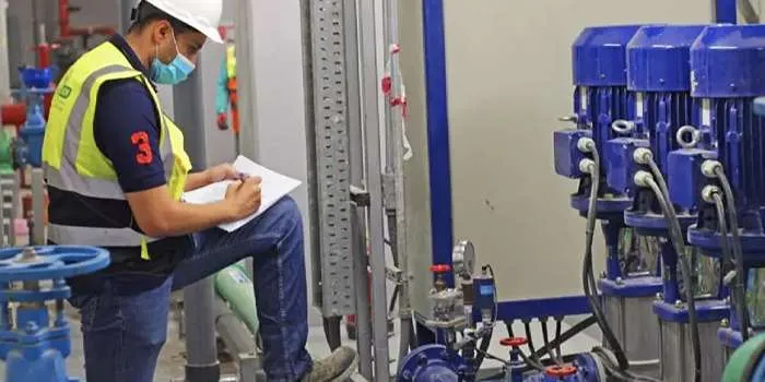 تصویری از شخصی با لباس کار در حال چک کردن تاسیسات ساختمانی